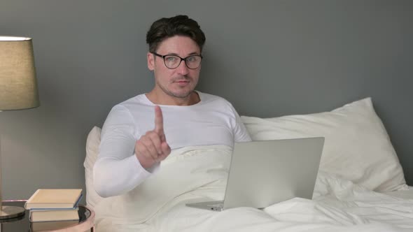 No Gesture with Finger By Middle Aged Man with Laptop in Bed  alt