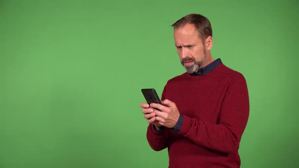 A Middleaged Handsome Caucasian Man Works on a Smartphone and Acts Frustrated  Green Screen