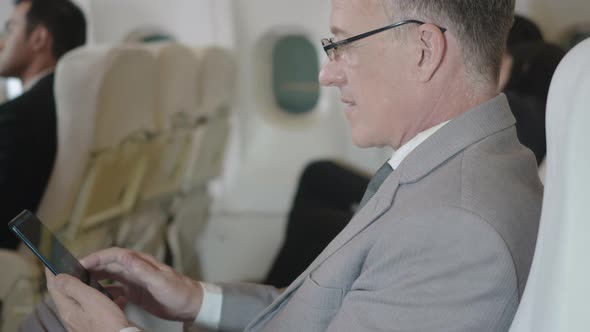 businessman using wifi texting mobile phone sitting in airplane he's toughing smartphone screen alt