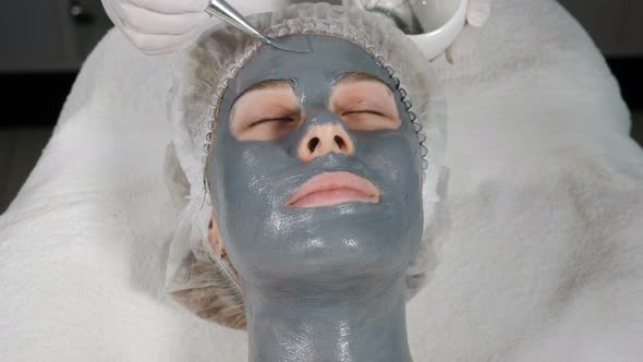 Top View of Female Client Getting Facial Beauty Treatment. Applying Facial Mask To Face Skin at alt
