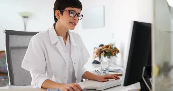 Beautiful Female Doctor Typing Receipt for Patient