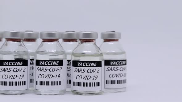 Corona Virus Vaccine In Bottle Over White Background - panning shot alt
