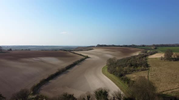 Drone shot flying over fields and farms in Hampshire, Britain on sunny day alt