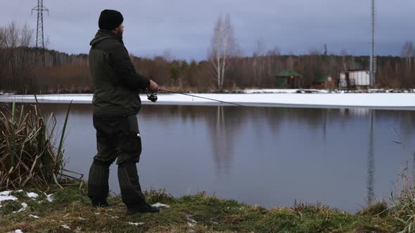 Unrecognizable Man Fishing in Lake at Dawn