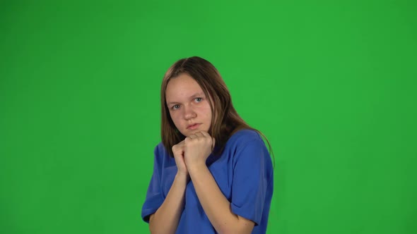 Teen Girl Is Scared and Hiding Her Face in Studio on Green Background. alt
