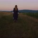 Woman in ukrainian national clothes walking on wheat field and mountains