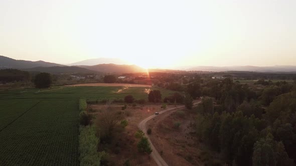 Aerial drone shot flying forward over a gravel road with green fields being watered and an amazing s alt