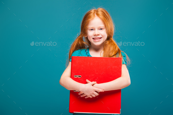 Pretty, cute little girl in blue clothes with long red hair cares papers