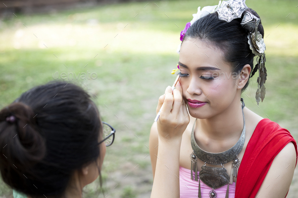 Make up artist making up eye liner to Thai woman wearing thai traditional clothing