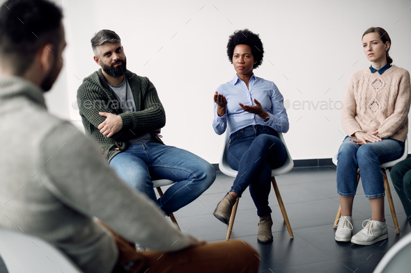African American mental health professional talking to group of people during a session.