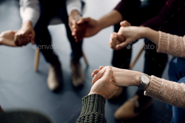 Close-up of attenders of group therapy holding hands during the meeting. - Stock Photo - Images