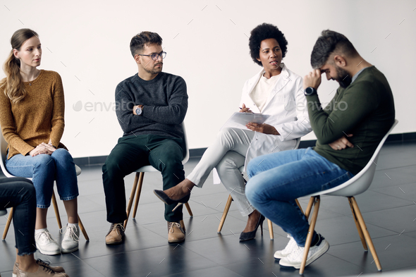 African American psychotherapist talking to participants of a group therapy.
