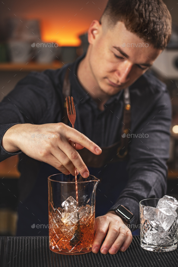 Young barman stirring fresh alcoholic cocktail - Stock Photo - Images