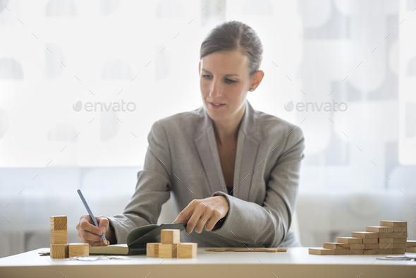 Woman writing on notepad beside wooden blocks - Stock Photo - Images