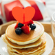 Pancakes with berries, roses flowers, cup of tea and candle in candlestick. Valentine&#39;s day concept - PhotoDune Item for Sale