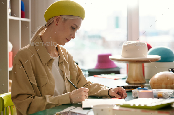 Side view of young creative hat designer drawing sketches - Stock Photo - Images