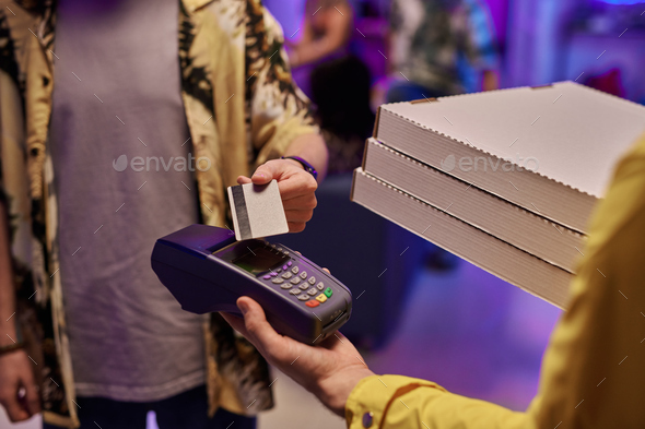 Young man paying by credit card for ordered pizza held by deliveryman - Stock Photo - Images