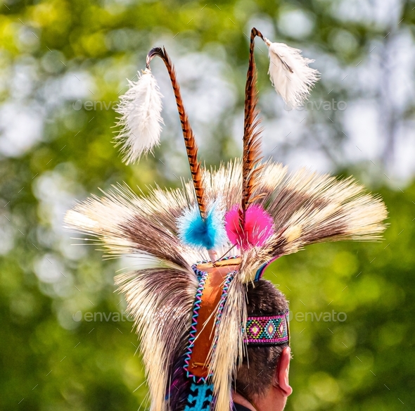Closeup shot of the head of a person in a traditional Indian-American festive hat with feathers