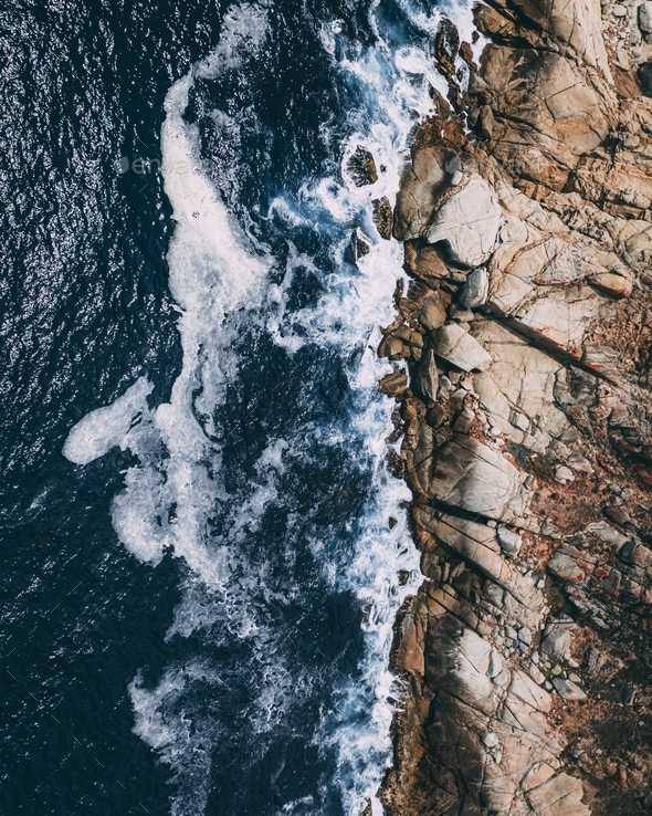 Top view of a rocky shoreline with waves hitting the rocks