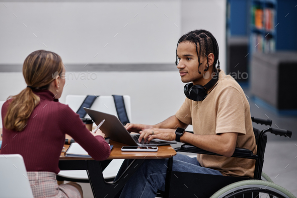 Young black boy with disability studying in college library with friend - Stock Photo - Images