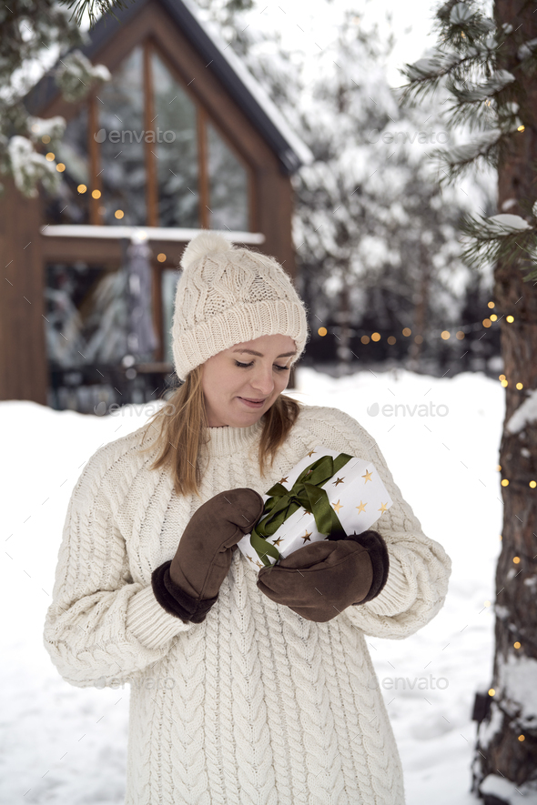 Caucasian woman holding Christmas present  in front of house - Stock Photo - Images