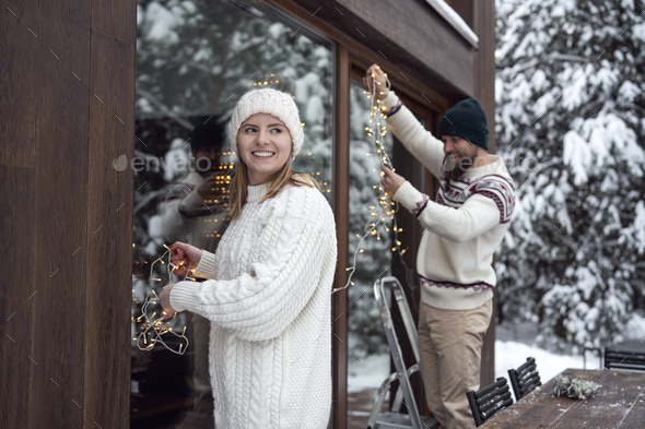 Caucasian couple decorating home for Christmas in lights - Stock Photo - Images