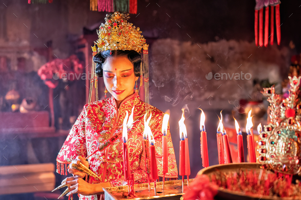 Woman traditional dress in Chinese shrine light up candle joss stick ...