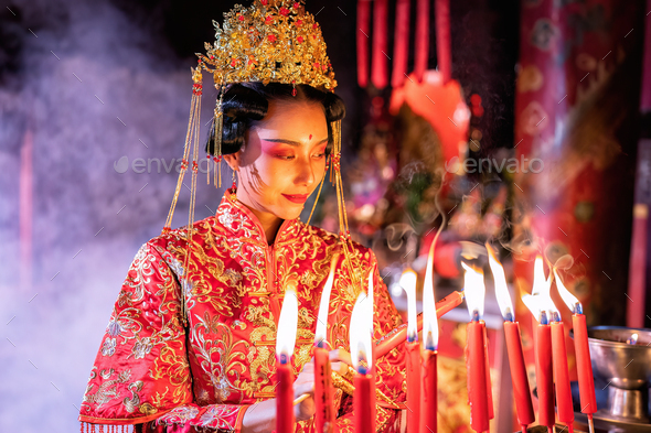 Woman traditional dress in Chinese shrine light up candle joss stick ...