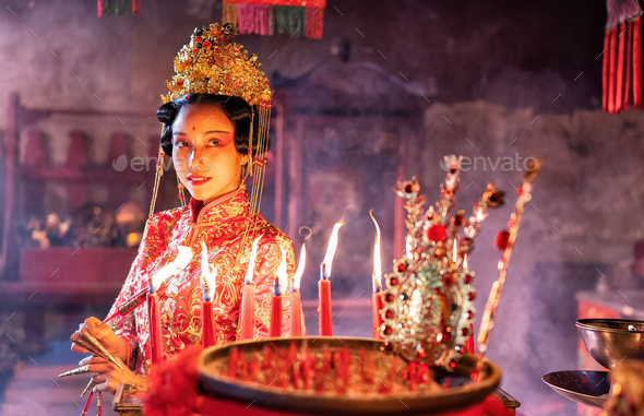 Woman traditional dress in Chinese shrine light up candle joss stick ...