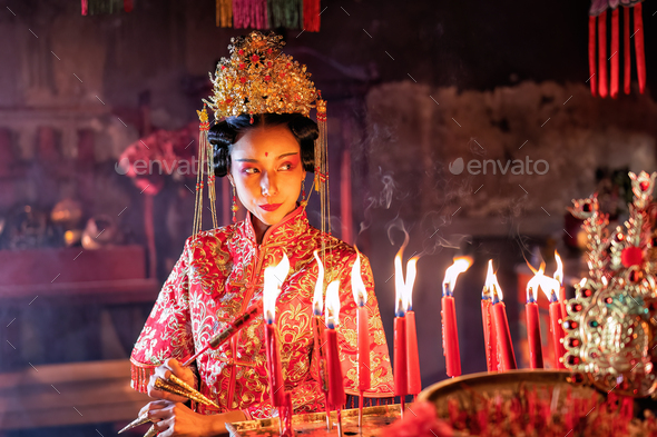 Woman traditional dress in Chinese shrine light up candle joss stick ...