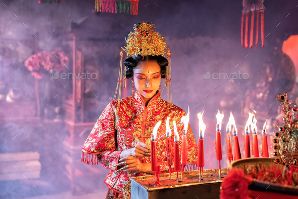 Woman traditional dress in Chinese shrine light up candle joss stick ...