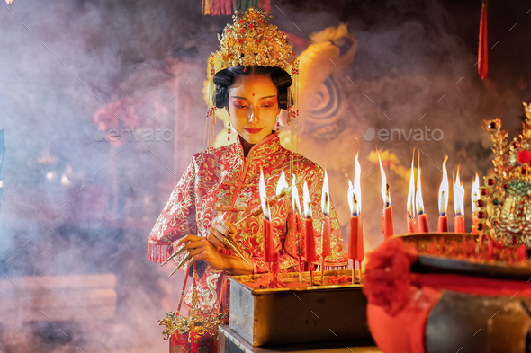 Woman traditional dress in Chinese shrine light up candle joss stick ...