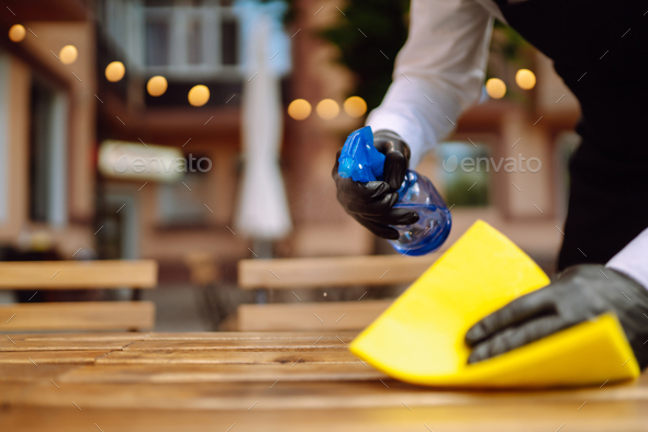 Waiter cleaning the table with spray disinfectant on table in