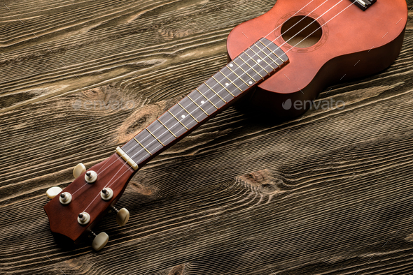 Hawaiian ukulele guitar on brown wooden background. - Stock Photo - Images