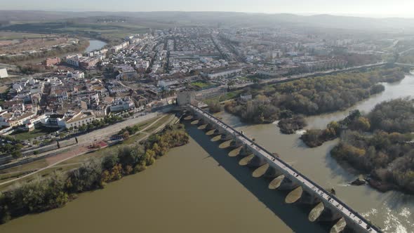 Descending drone shot towards Roman bridge and Cordoba gate-tower museum
