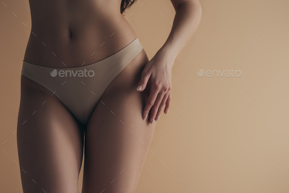 Cropped view of sexy woman in panties touching hip isolated on beige Stock  Photo by LightFieldStudios