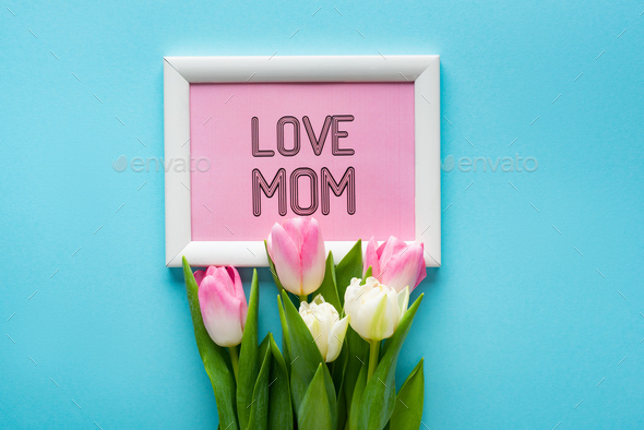 Top view of tulips on frame with i love mom lettering on blue background