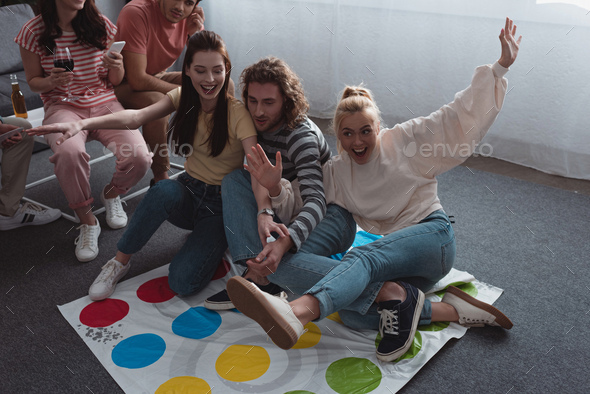 KYIV, UKRAINE - JANUARY 27, 2020: high angle view of friends sitting on twister game mat while
