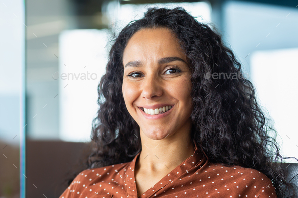 Close-up portrait of beautiful Latin American businesswoman smiling and looking at camera, working - Stock Photo - Images