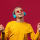 Positive man listening music, enjoying dance with headphones on red studio background.  - PhotoDune Item for Sale