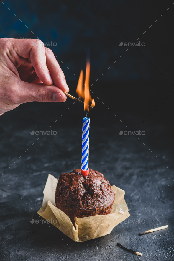 Hand lighting candle on birthday muffin - Stock Photo - Images