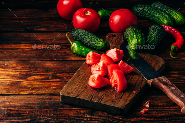 Sliced tomatoes on cutting board and cucumbers with chili pepper - Stock Photo - Images