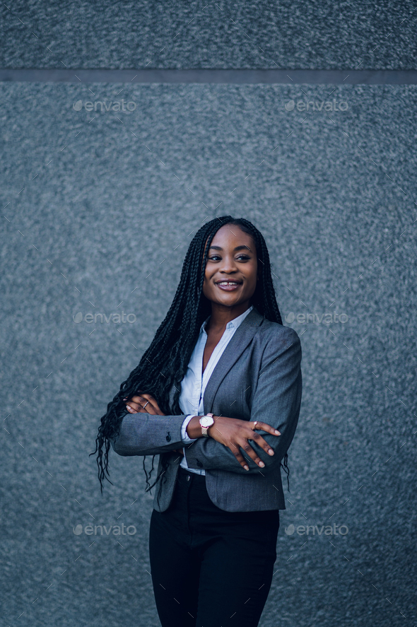 Beautiful female african american business woman CEO in a suit at the  workplace, standing confidently with arms folded Stock Photo
