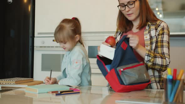 Pregnant Mother Giving Lunch Box To Cute Daughter Saying Good-bye Before School alt