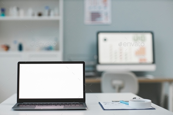 Laptop with blank white screen standing on desk against computer monitor - Stock Photo - Images