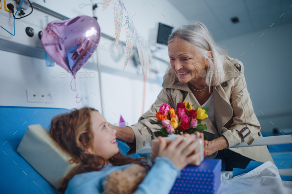 Granmother visiting her sick granddaughter in hospital, celebrating her birthday. - Stock Photo - Images
