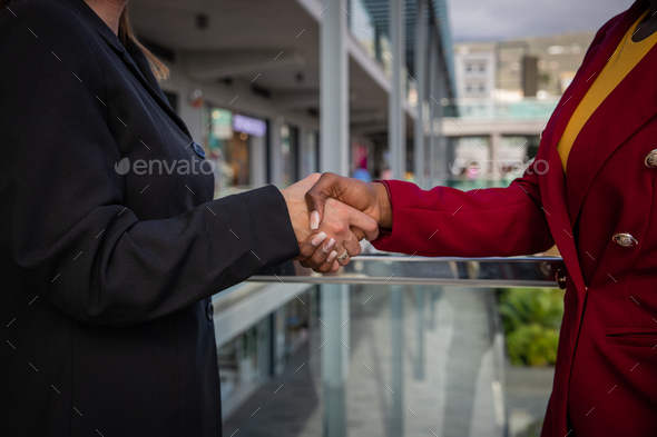 Two businesswomen, caucasian and african shaking hands, done deal concept.
