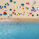 Aerial view of umbrellas on sandy beach, people in blue sea - PhotoDune Item for Sale