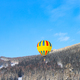 flying yellow hot air balloon over winter mountains - PhotoDune Item for Sale
