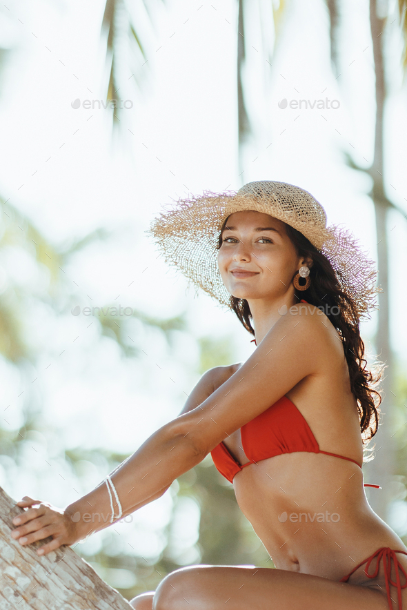 Summer Lifestyle Funny Portrait of Tanned Bikini Girl Model in Red Swimsuit on Palm Tree at the - Stock Photo - Images